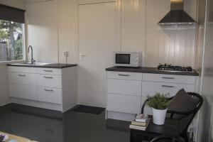 a kitchen with white cabinets and a sink and a microwave at Tiny House Madame Jeanette nabij centrum en zee in Zandvoort +8 photos