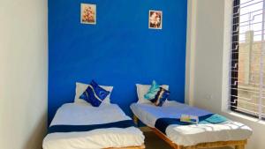 2 Betten in einem Zimmer mit blauer Wand in der Unterkunft Z Homes in Shamsgarh