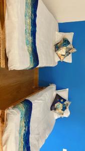 a bed with white sheets and pillows on a blue wall at Z Homes in Shamsgarh
