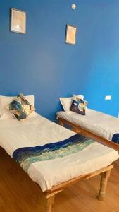 2 Betten in einem Zimmer mit blauer Wand in der Unterkunft Z Homes in Shamsgarh