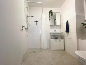 biała łazienka z prysznicem i umywalką w obiekcie Zentrales Innenstadt Studio mit Garage w Stuttgarcie