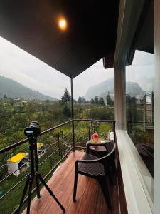 balcón con mesa y vistas a la montaña en Hotel Apple Flower, en Manali