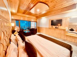 a bedroom with a bed and a flat screen tv at Pinewood Lodge in Ooty