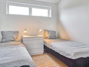 a bedroom with two beds and a dresser and a window at Holiday home Nexø IX in Neksø