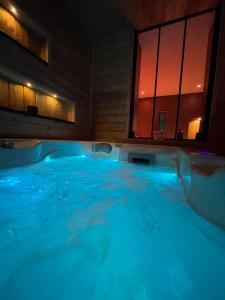 jacuzzi con iluminación azul en una habitación en Au Plaisir Vosgien, en Raon-lʼÉtape