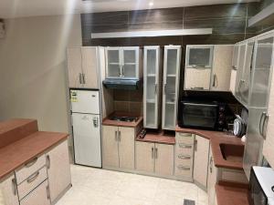 a kitchen with white cabinets and a white refrigerator at سفانه in Unayzah