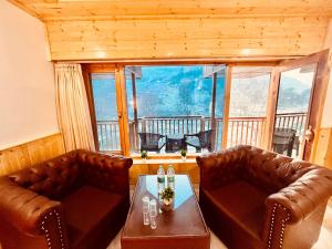 a living room with two leather chairs and a table at Pinerock hotel in Mussoorie