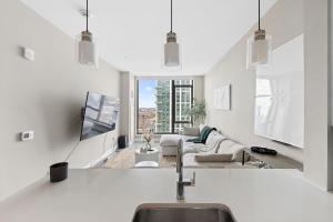 a white living room with a couch and a tv at Boston West End Penthouse Edition in Boston