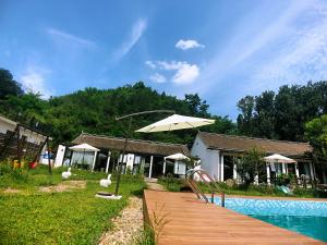 a wooden walkway with an umbrella next to a pool at 隐谷私院The Great Wall Valley in Gubeikou