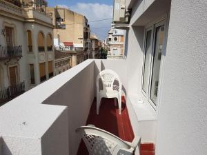 2 sillas blancas sentadas en el balcón de un edificio en Hotel Maritimo, en Alicante