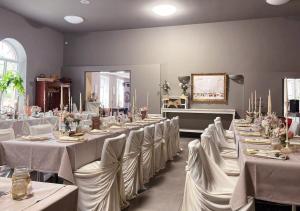 Zimmer mit langen Tischen und weißem Tischtuch in der Unterkunft Pension EssLust in Niedergörsdorf
