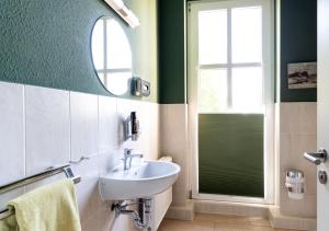 ein Bad mit einem Waschbecken und einem Spiegel in der Unterkunft Pension EssLust in Niedergörsdorf