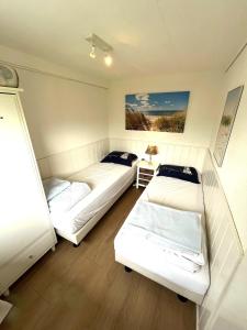 Habitación con 3 camas en una habitación en Vakantiebungalow in Riviera Maison stijl nabij zee en strand, bos en duin, en Warmenhuizen