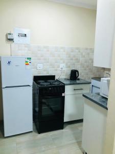  La cuisine est équipée d'une cuisinière noire et d'un réfrigérateur. dans l'établissement Peshline Guest House Unit 3, à Ermelo