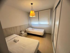 een kleine kamer met 2 bedden en een licht bij Sidi Luxury 2 (Beach & Golf) in Alicante +18 foto's