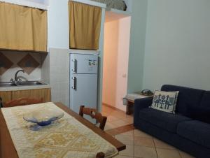 eine Küche mit einem Tisch, einem Sofa und einem Kühlschrank in der Unterkunft Edera Apartment# Tanaunella# Budoni# Beach in Budoni