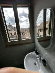 La salle de bains est pourvue d'un lavabo, d'un miroir et d'une fenêtre. dans l'établissement Casa in centro, à Foligno