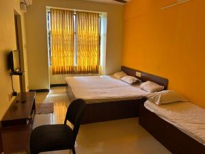 um quarto com 2 camas, uma cadeira e uma janela em Aishvarya Residency Coimbatore em Coimbatore