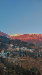 a town on a hill with mountains in the background at Vibes by Vicctoria House in McLeod Ganj