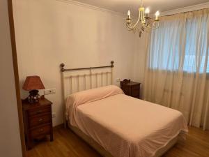 1 dormitorio con cama, lámpara y ventana en apartamento Marina en Ribeira