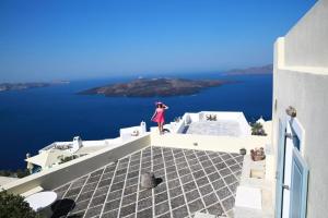 a woman standing on the roof of a building overlooking the ocean at Beautiful Santorini Villa | Villa Galázio | 2 Bedrooms | Private Terrace & Breathtaking Caldera Views | Fira in Fira