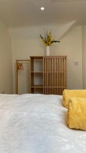 a large white bed with a yellow blanket on it at Spire attic apartment no kitchen in Dublin