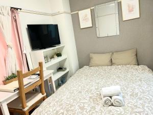 Dormitorio pequeño con cama y TV en COCO Nakameguro302, en Tokio