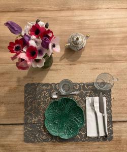 Maison d hôtes LA VILLA MADELEINE في ساناري سور مير: طاولة مع صحن و إناء من الزهور