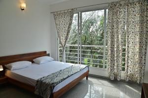 DharmastalaBougainvillea Residency的一间带床和大窗户的卧室
