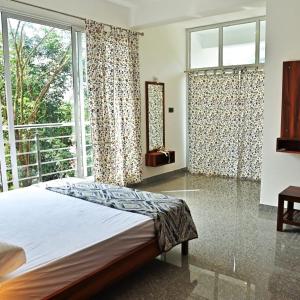 DharmastalaBougainvillea Residency的一间带床和大窗户的卧室