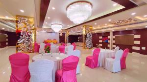 um salão de banquetes com mesas e cadeiras cor-de-rosa e brancas em Aradhana inn em Lucknow