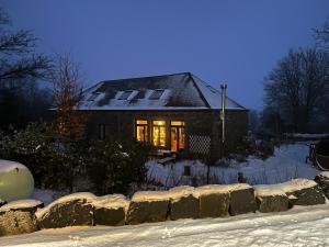 une maison dans la neige avec les lumières allumées dans l'établissement Ecole Buissonnière, à Vielsalm