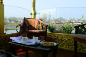 Floating Luxury Group Of Houseboats في سريناغار: طاولة مع غلاية الشاي وصحن من الطعام