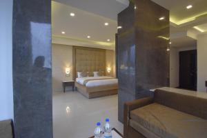 een slaapkamer met een bed en een bank met flessen water op een tafel bij Gourav Lodge in Jodhpur