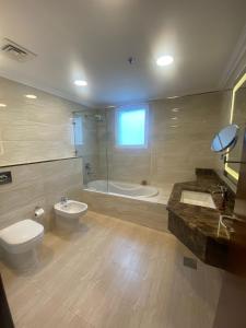 a bathroom with a toilet and a tub and a sink at A Line Hotel in Doha