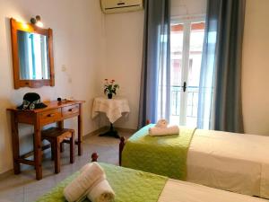 a bedroom with two beds and a desk and a window at Nikos Apartments 2 in Kavos