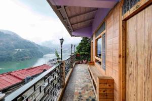 a house with a balcony with a view of a river at Goroomgo Vinayak Mall Road Lake View Nainital - Luxury Room - Best Hotel in Nainital in Nainital