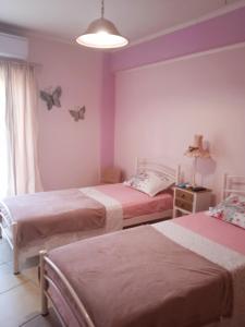 twee bedden in een kamer met vlinders aan de muur bij Nicole's home! in Nafpaktos