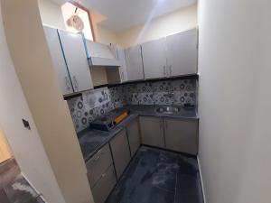 a small kitchen with white cabinets and a sink at Sajid Apartment Murree in Murree