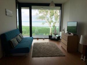 a living room with a blue couch and a large window at AMP Apartman - Siófok in Siófok