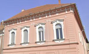 un edificio rosa con ventanas blancas encima en Classic Deluxe Tapolca, en Tapolca