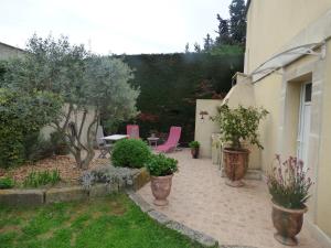 un patio con sillas rosas, mesa y árboles en Chambre d'Hôtes entre Provence et Camargue en Beaucaire