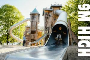 a boy sitting on a slide at a playground at Camping Fuussekaul in Heiderscheid