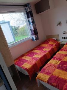 two beds in a room with a window at Mobilhome Baltique in Oye-Plage