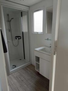 a white bathroom with a shower and a sink at Mobilhome Baltique in Oye-Plage