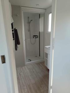 uma casa de banho com um chuveiro e uma porta de vidro em Mobilhome Baltique em Oye-Plage