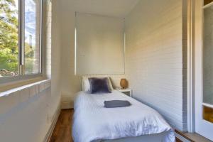 a small bed in a room with a window at Charming 3 Bedroom on the edge of Downtown Herford St 2 E-Bikes Included in Sydney
