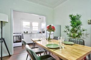 a kitchen and dining room with a wooden table and chairs at Charming 3 Bedroom on the edge of Downtown Herford St 2 E-Bikes Included in Sydney