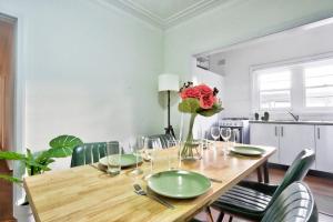 a dining room table with green chairs and a vase of flowers at Charming 3 Bedroom on the edge of Downtown Herford St 2 E-Bikes Included in Sydney