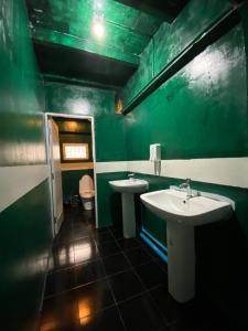 a green bathroom with two sinks and a toilet at Happiness Community Wake & Bake Hostel - Rooftop Bar & Bistro in Pattaya